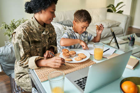 Boy sitting at the table and eating cupcakes with juice at the breakfastの写真素材