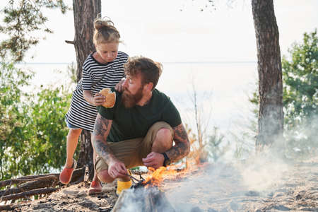 Happy family basking near the fire at the cozy forestの写真素材