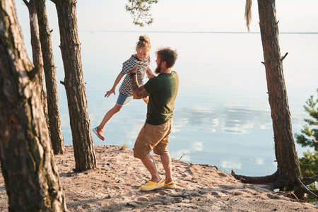 Girl laughing out loud and feeling great while her beloved father holding her at handsの写真素材