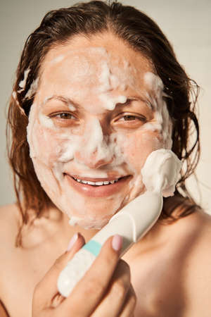 Woman having spa procedures and laughing to the camera with mask on her faceの写真素材