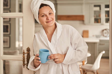 Oversize smiling woman standing with cup at homeの写真素材