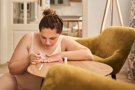 Oversize woman painting nails with nail polishの写真素材