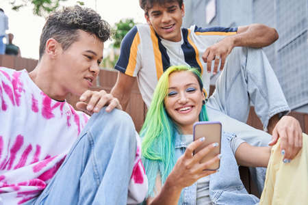 Girl and guys watching something on mobile phoneの写真素材