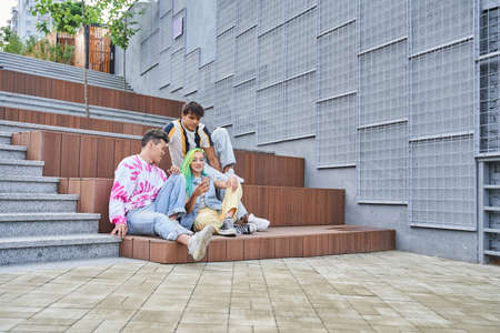 Best friends sitting at the stairs and watching something at the smartphoneの写真素材