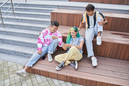 Girl and guys watching something on mobile phoneの写真素材