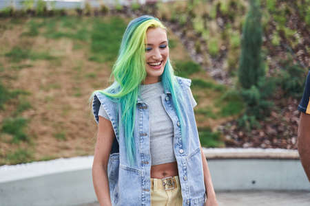 Young girl with color hair laughing out loud while walking at the streetの写真素材