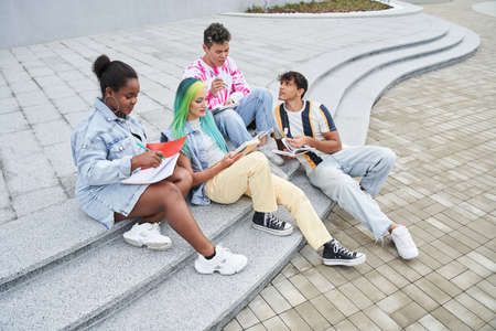 Different races friends doing homework in city