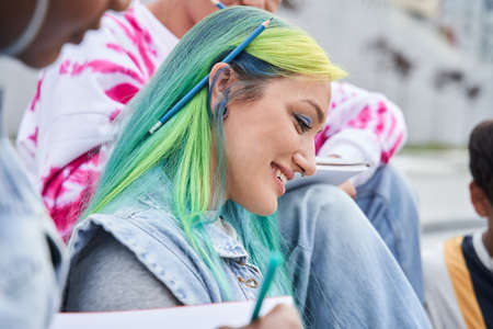 Concentrated students reading something while learning at the streetの写真素材