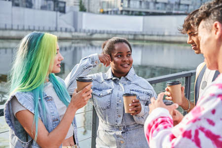 Friends holding cups with coffee while enjoying of the hot beverageの写真素材