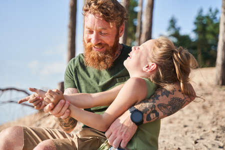 European father hugging daughter on sandy coast