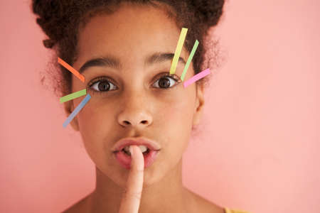 Girl making silence gesture with finger on her lips and keeping some secret