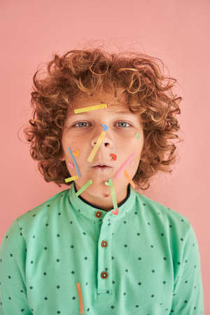 Boy with stylish hair and color stickers at his face looking at the camera with funny faceの写真素材