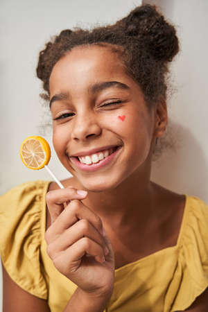 Girl holding sweet lollypop with happy expression and smiling to the camera