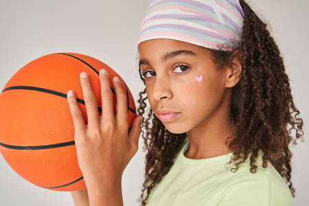 Child girl posing with ball of basketball to the camera over isolated white backgroundの写真素材