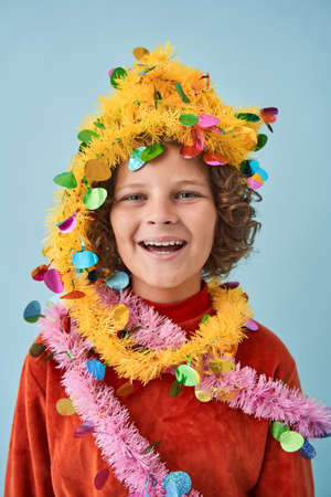 Boy wrapped in a festive garland and laughing out loud while posingの写真素材