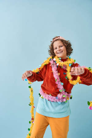 Boy wrapped at festive garland and feeling great while posing at the studio