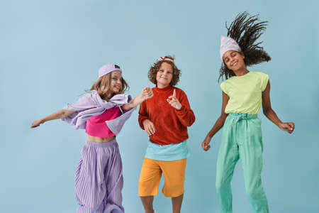 Diverse best friends wearing urban clothes dancing and jumping with happy smilesの写真素材