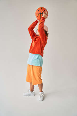 Curly european little boy throwing basketball ballの写真素材