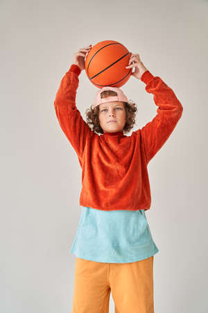 Curly european little boy holding basketball ballの写真素材
