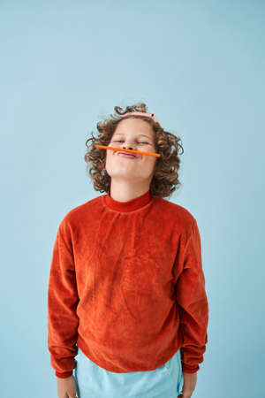 Little boy joking while holding pencil over mouthの写真素材