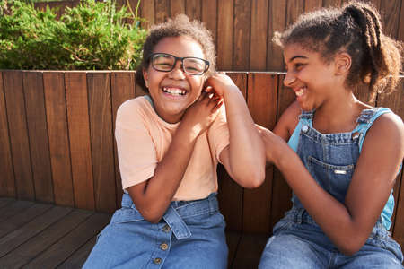 Girlfriends sitting on wooden bench and joking