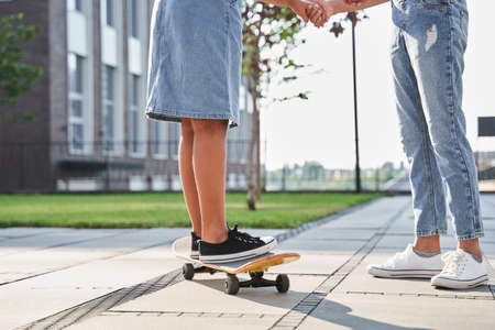 Little girl teaches girlfriend riding on skateboard
