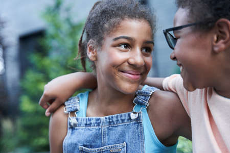 Little black girls sitting and embracing outdoorの写真素材