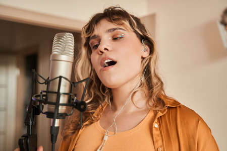 Woman singing in microphone at home music studioの写真素材