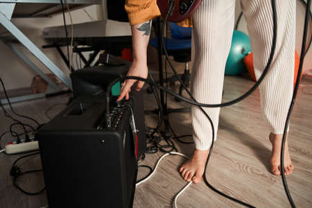 Girl turn on guitar amplifier at home music studio