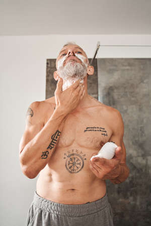 Mature man applying shaving foam on beard on neckの写真素材