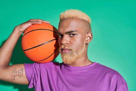 Guy in casual clothes holding ball at his shoulder and looking at the cameraの写真素材