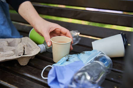 Woman sitting at the bench fool of rubbish and holding her coffeeの写真素材