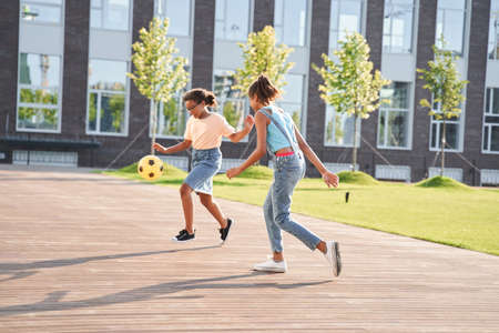 Little girlfriends playing football on wooden areaの写真素材