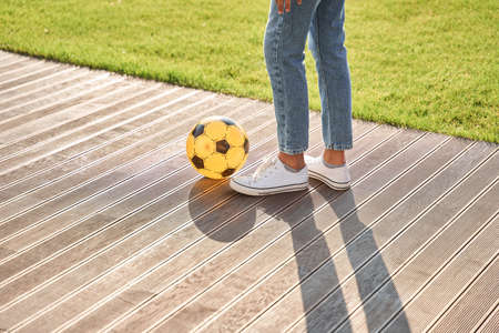 Little girl with football ball on wooden areaの写真素材