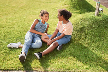 Little black girlfriends resting on green grassの写真素材