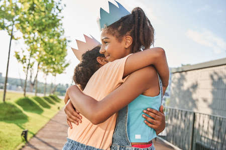 Little girls in paper crowns standing and huggingの写真素材
