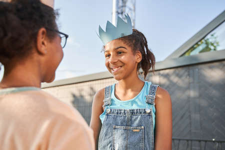Little girls in paper crowns looking at each otherの写真素材