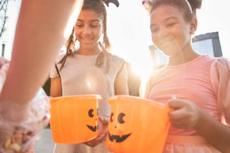 Girls hold buckets and wait for treats on halloweenの写真素材