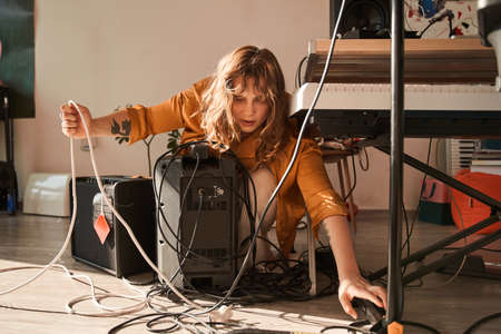 Oversize woman fixing wires of musical equipmentの写真素材