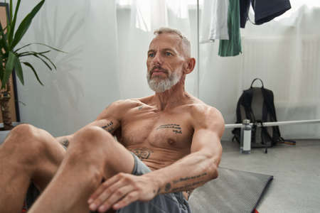 Mature man doing crunching on fitness mat at homeの写真素材