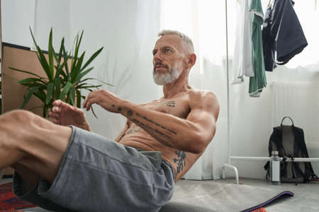 Mature man doing crunching on fitness mat at homeの写真素材