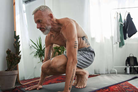 Mature man doing sport exercise on fitness matの写真素材