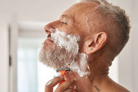Handsome man is shaving in the bathroomの写真素材