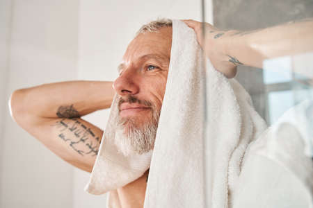 Man wiping his head with white towel at the morningの写真素材