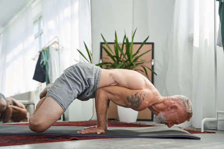 Senior man holding his body at the hands while enjoying meditationの写真素材