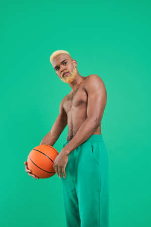 Bearded handsome athlete posing with orange ball and looking at the cameraの写真素材