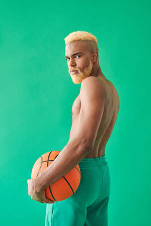 Guy with blonde hair holding ball and looking at the camera over his shoulderの写真素材