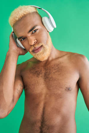 Multiracial man with blonde hair using headphones while enjoying of the musicの写真素材