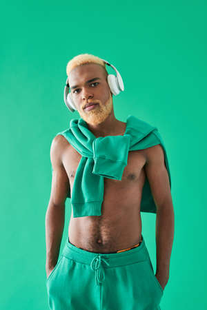 Serious man wearing headphones looking at the camera on green backgroundの写真素材