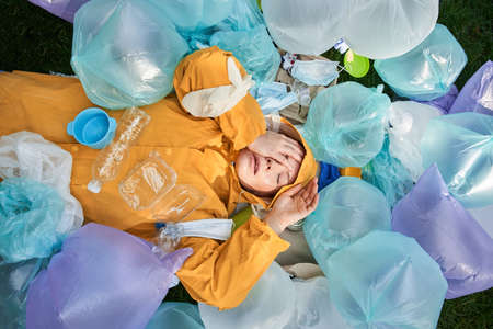 Blonde girl closed eyes with her hands among the rubble of trashの写真素材